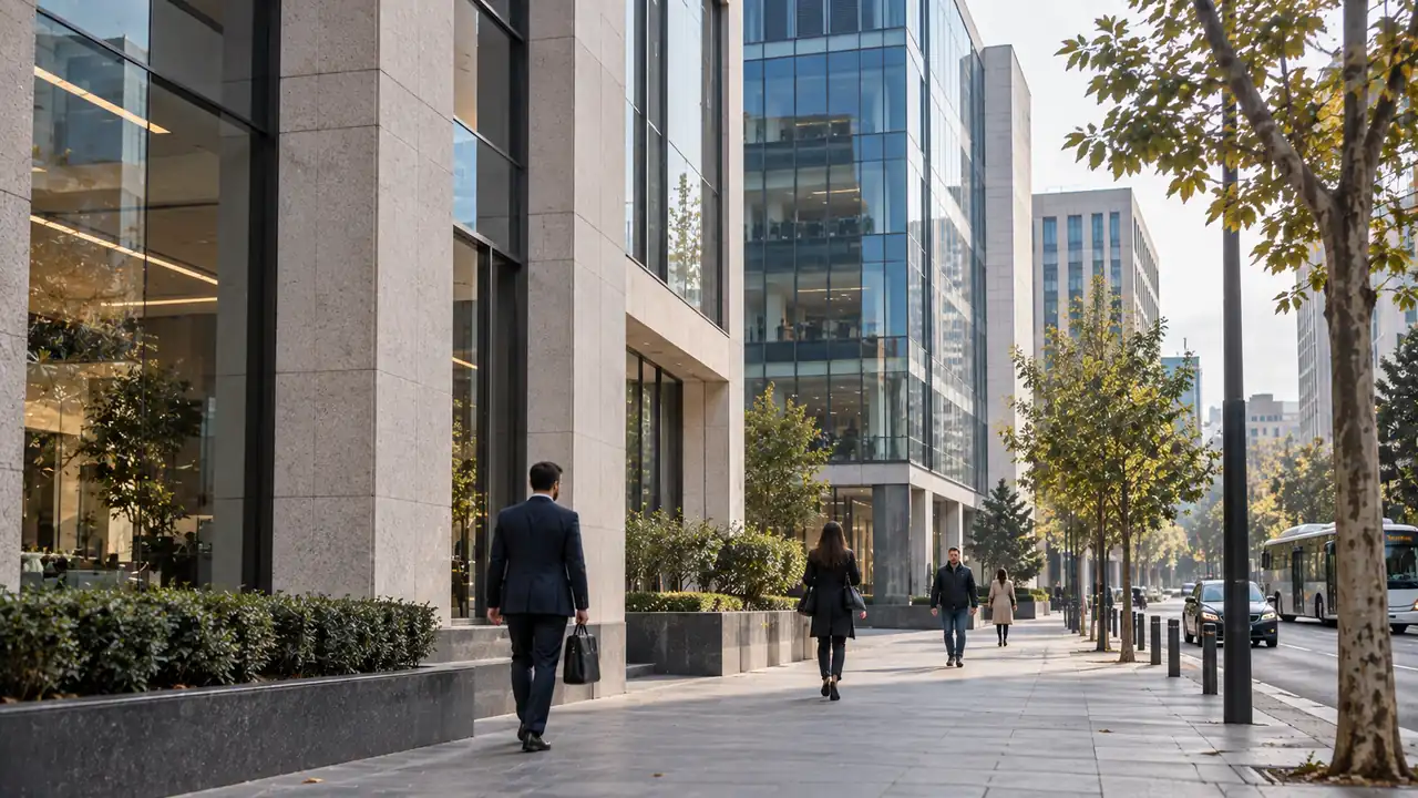 People walking past glass-fronted office buildings on a tree-lined business district street